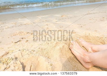 Man and woman's feet on a sunny beach sand by the ocean. Copy space at the top. Abstract of summer holidays.
