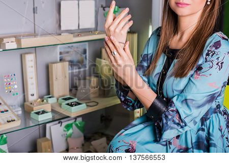 beautiful woman buyer chooses jewelry. In the background showcase with jewelry.Concept of luxurious and wealth life