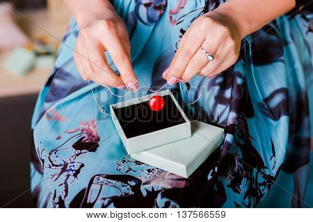 Woman keeping silver necklace with red enamel Jewelry. closeup hands. Concept of luxurious and wealth life