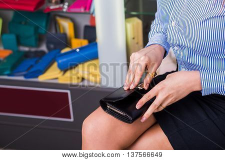 Shop accessories. Business buyer opens wallet beautiful female hand closeup. behind Showcases with accessories