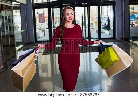 Portrait of beautiful happy welldressed woman with shopping bags. Shopping center. Successful  day.