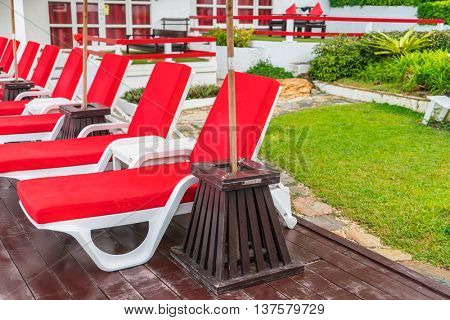 Beautiful beach chairs with umbrella around outdoor swimming pool neary sand and sea