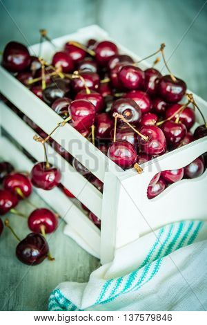 Cherries in a white wood crate over a wood background