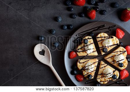 Waffles with blueberries, strawberries, whipped cream and chocolate sauce