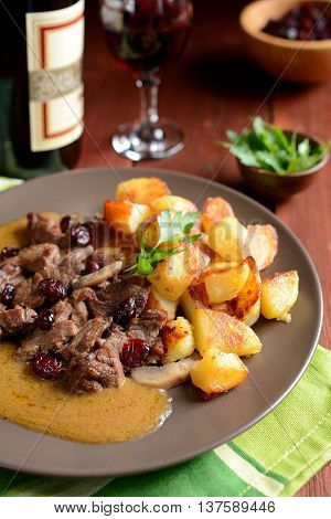 Wild boar meat with roasted potatoes, mushrooms and cranberries