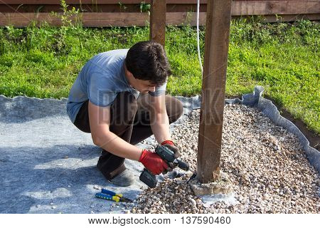 Man Fixes Electrical Cord On A Wooden Post
