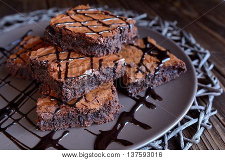 Chocolate brownies on a brown plate and wooden background