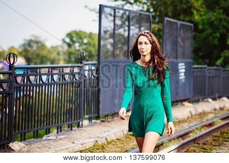 Girl walking along the road in the city, Sunny summer day, developing green dress