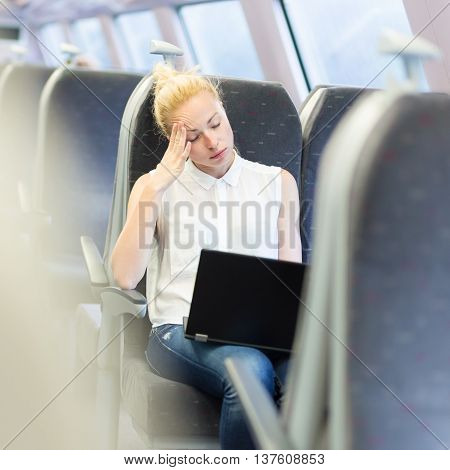 Businesswoman naping sitted while traveling by train and working on laptop. Tiresome business travel.