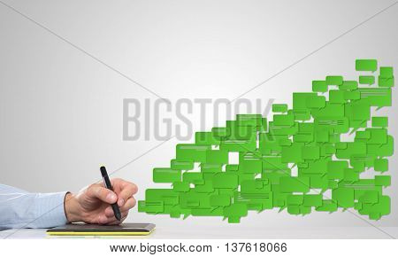 Hand of man using tablet and chatboxes flying out