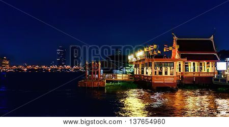 Atmosphere of night Bangkok Thailand. Classical Thai architecture with night lights modern skyscrapers and Krung Thon Bridge on Chao Phraya river. Made with grainy Colored Filters and Soft Focus