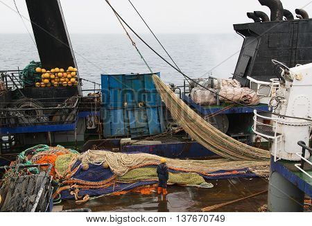 The Bering Sea Russia - Jun 18th 2016: The Bering Sea fishing seiner VLADIMIR STARZHINSKY the seaman to place a fishing net on a deck.