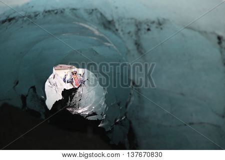 ICELAND - JULY 4, 2016: Tour guide exploring ice cave at Solheimajokull glacier. Solheimajokull glacier is one of the biggest glaciers in Europe