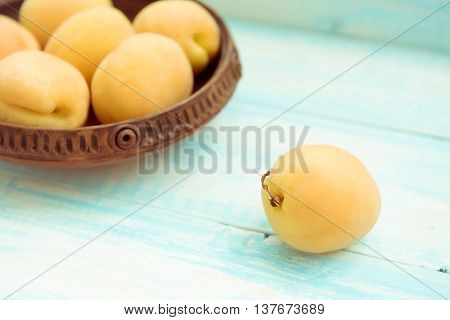 Fresh ripe apricots in vintage bowl on turquoise wooden background