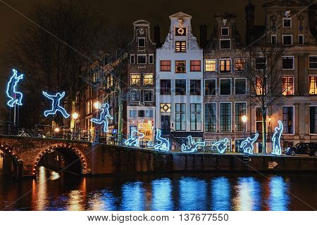 Amsterdam Netherlands - December 18 2015: Light Festival Amsterdam a light figure makes a somersault with as decor Amsterdam Canal Houses and bridge