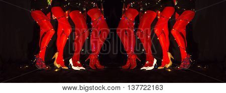 Legs of female cabaret dancers with christmas lights tied around body in red leggings and high heels shoes on dark background