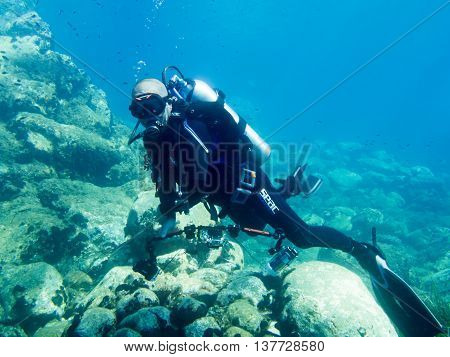 Avlaki Greece - June 15 2016 : A male scuba diver with a camera shows good buoyancy during a dive