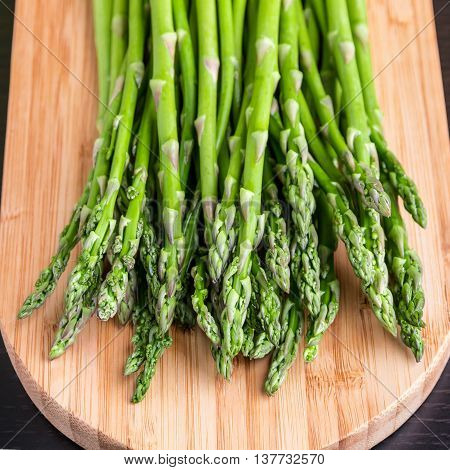Close up of fresh asparagus on wooden board. Selective focus on tips of asparagus.