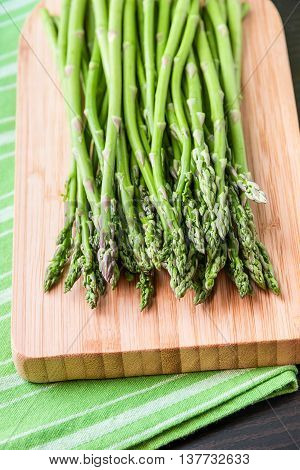 Close up of fresh asparagus on wooden board. Selective focus on tips of asparagus.