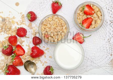 Ripe and tasty strawberries with scattered muesli on white background