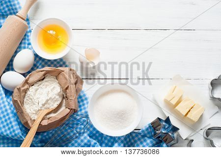 Ingredients for cooking baking - flour, egg, sugar, rolling pin on white wooden table.