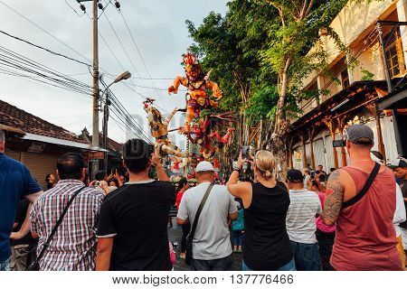 KUTA, INDONESIA - MARCH 08: Tourists take photo of the Ogoh-ogoh statues at the parade on the eve of Nyepi day on March 08 2016 in Kuta Bali Indonesia