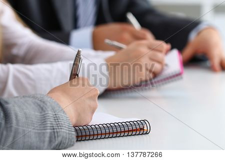 Close up view of students or businesspeople hands writing something during conference. Business meeting blogging or professional education concept