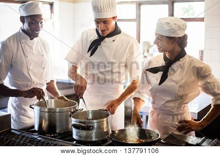 Chefs preparing food at stove in commercial kitchen