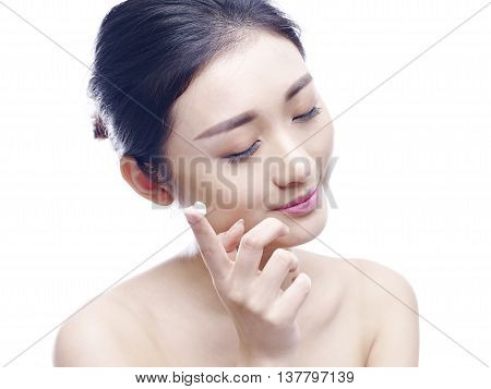young asian woman applying lotion or cream to face isolated on white background.