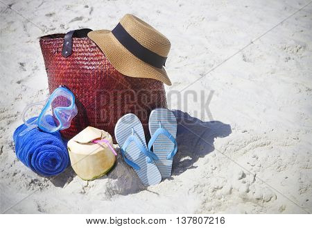 Straw hat wather mask beach towel flip flops with beach bag and coconut cocktail. Summer travel and vacation concept