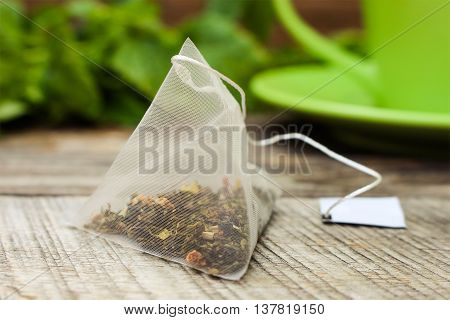 Tea bag on background of mint and and green cup