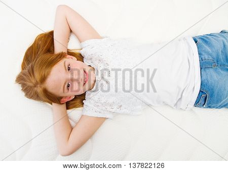 Young girl is lying on the bed. Quality mattress.