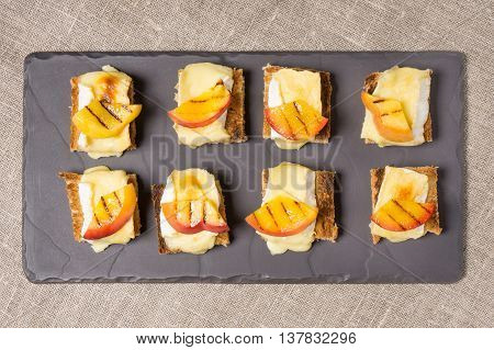 canapes appitizer with grilled brie and nectarine plated on a slate dish