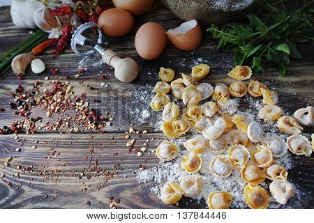 Homemade pasta ravioli on old wooden table with flour eggs kitchen italian herbs - cooking concept