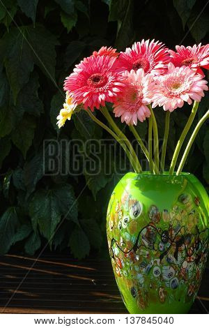 Colorful gerbera daisies in green vase made from mosaic murano glass