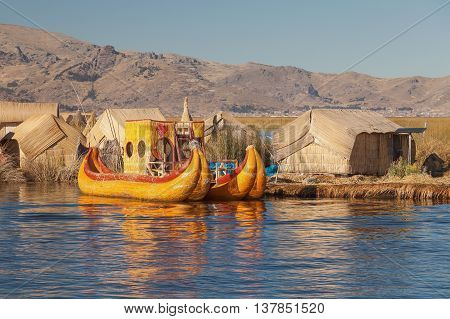Reed boat on Island of Uros. Those are floating islands on lake Titicaca located between Peru and Bolivia. Colorful image with yellow boat and clear blue sky.
