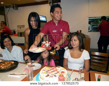 CEBU CITY, CEBU / PHILIPPINES - AUGUST 12, 2011: A waiter at Pizza Hut serves slices of birthday cake at a birthday party in the restaurant in the SM City Cebu shopping mall.