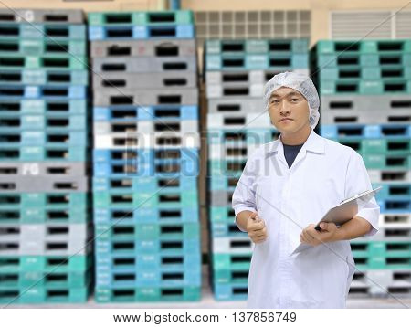 A man in white great coat uniform and Plastic Pallets of background for Concept design Quality Inspection Business.