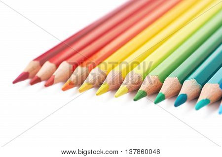 Multiple colorful color pencils composition arranged in a line to form a rainbow gradient, composition isolated over the white background, close-up crop fragment