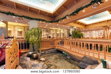 MOSCOW/RUSSIA - DECEMBER 2014. The interior of the deluxe restaurant of Uzbek cuisine - Babay Club in an oriental style. Pond and wooden bridge in the restaurant