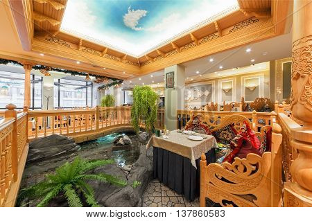 MOSCOW/RUSSIA - DECEMBER 2014. The interior of the deluxe restaurant of Uzbek cuisine - Babay Club in an oriental style. A table near the ornamental pond and a wooden bridge