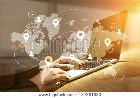 Global social networking concept. Side view of businessman hands using laptop with map network on wooden desktop