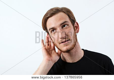 A Young Adult Male Wearing Dark T-Shirt with His Hand Near His Ear. Gestures Can Not Hear or Talk Louder. 