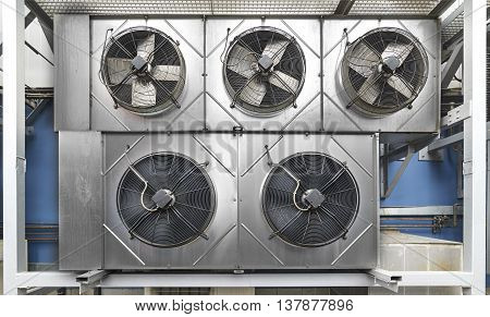 Industrial air conditioning units. Five cooling modules hang on the wall of a building.
