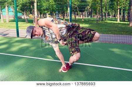 B-boy doing stunt trick on basketball playground with ball