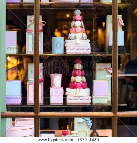 Beautiful colourful tasty macaroons cakes sweets and presents in the boxes display in window at the street shop