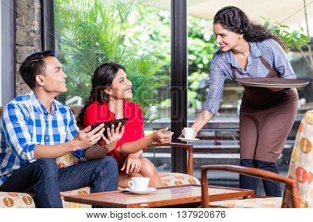 Indian waitress taking orders of two customers in cafe or restaurant