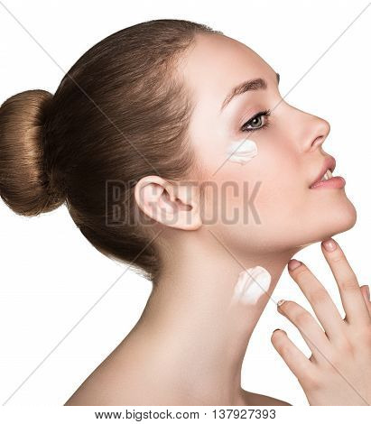 Beautiful model applying cosmetic cream on her face isolated on white
