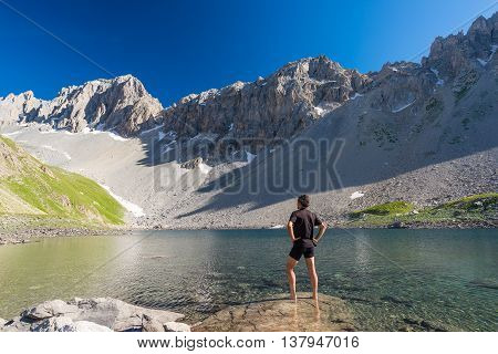 Hiker Relaxing At High Altitude Blue Lake In Idyllic Uncontaminated Environment Once Covered By Glac