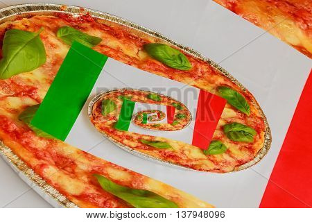 typical italian pizza made of tomatobasil and mozzarella with the italian flag in the background